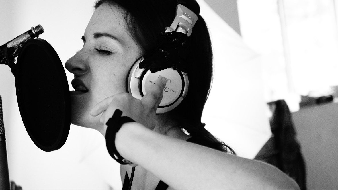 Chanteuse en pleine session d'enregistrement dans un studio, casque sur les oreilles