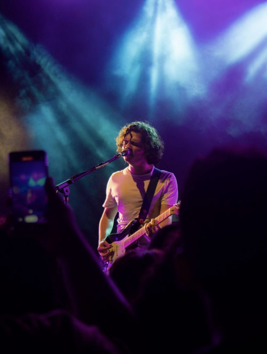 Artiste chantant et jouant de la guitare sur scène sous des lumières de concert
